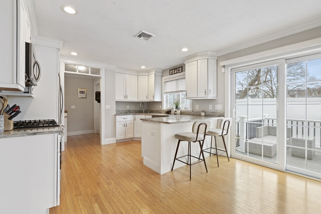 113 Elm Street, Unit D Quincy, MA 02169 - Photo 9 of 39 a kitchen with stainless steel appliances granite countertop a stove top oven a sink a refrigerator white cabinets and wooden floor