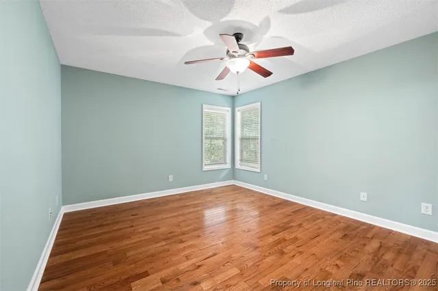 a view of an empty room with window and chandelier fan