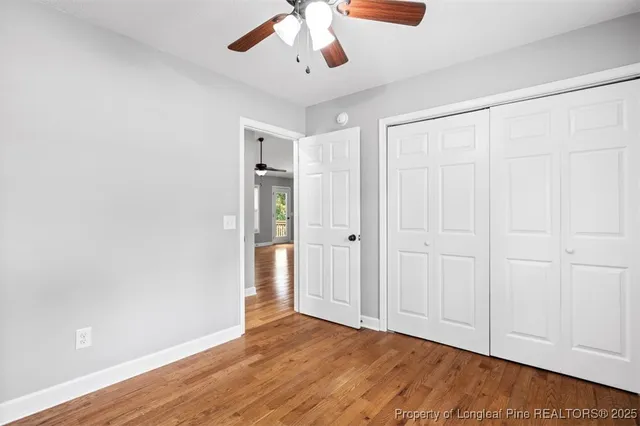 an empty room with wooden floor closet and windows
