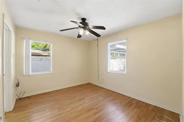 a view of an empty room with wooden floor and a window