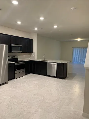 a large kitchen with stainless steel appliances a large counter top a stove and a refrigerator