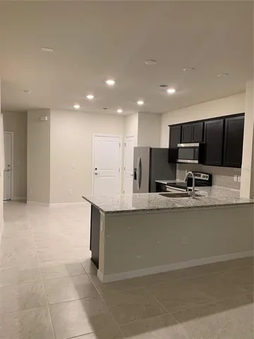 a large kitchen with stainless steel appliances a large counter top a stove and a sink with granite countertops