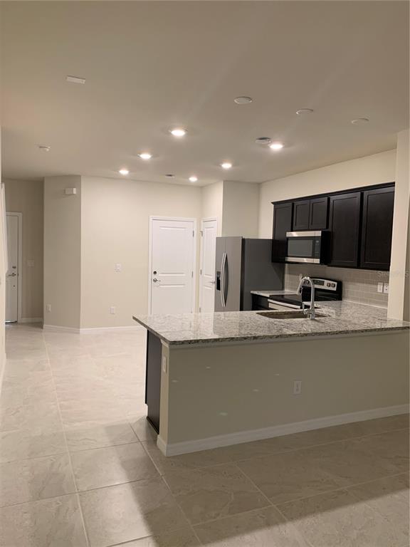 2559 Buena View Road Kissimmee, FL 34746 - Photo 3 of 17 a large kitchen with stainless steel appliances a large counter top a stove and a sink with granite countertops