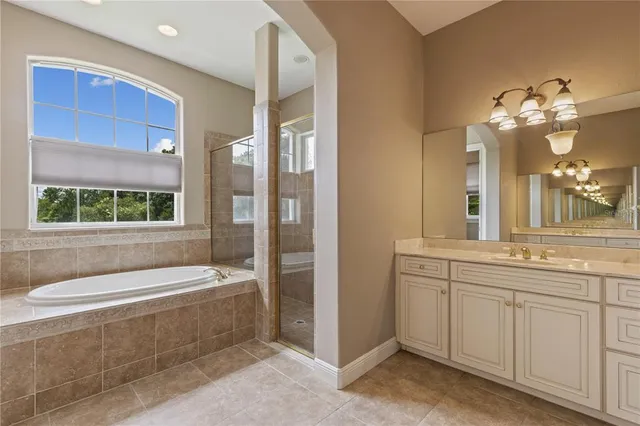 an empty room with chandelier fan and windows