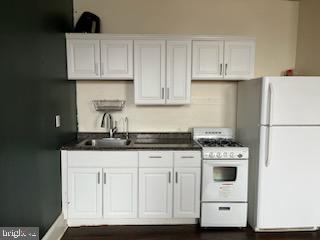 a kitchen with granite countertop a sink stove and white cabinets