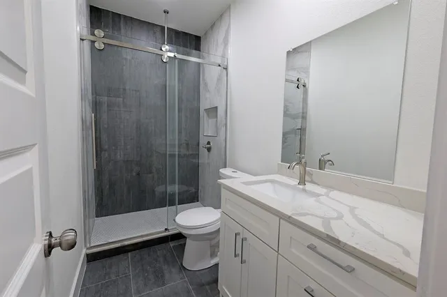 a bathroom with a granite countertop sink a toilet and shower