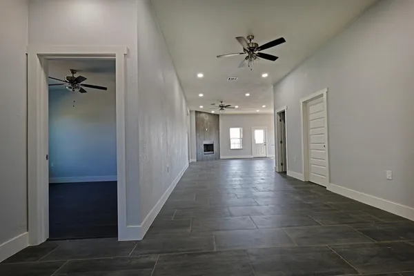 a view of a hallway with wooden floor and a ceiling fan