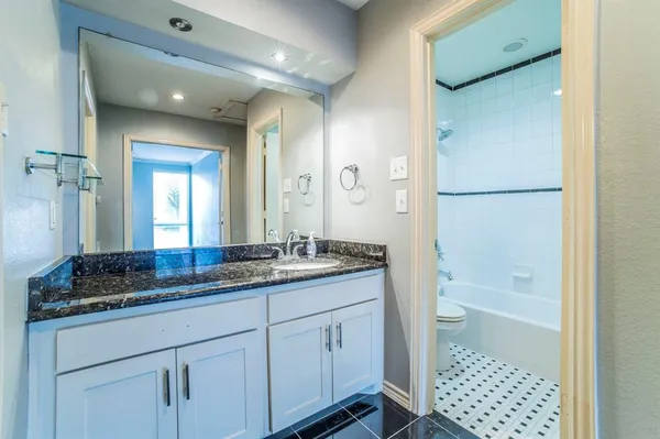 a bathroom with a granite countertop sink a mirror and a bathtub
