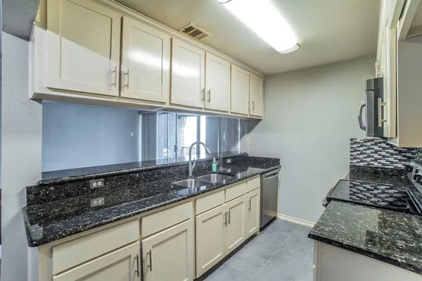 a kitchen with granite countertop stainless steel appliances a sink stove and cabinets