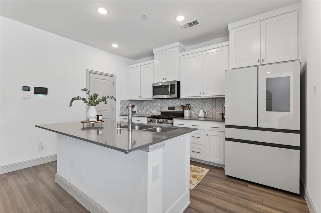 9000 Phoebe Road Frisco, TX 75035 - Photo 12 of 27 a kitchen with kitchen island white cabinets and stainless steel appliances