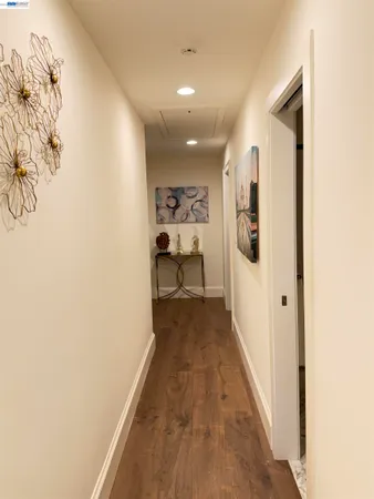 a view of a hallway with wooden floor and a bathroom