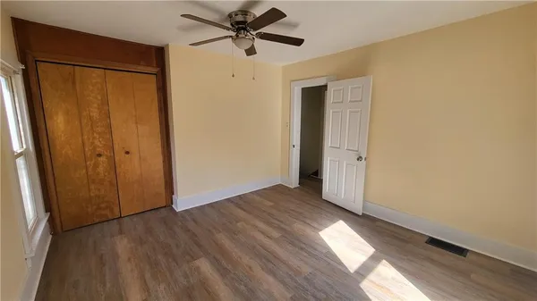 a view of empty room with wooden floor and fan