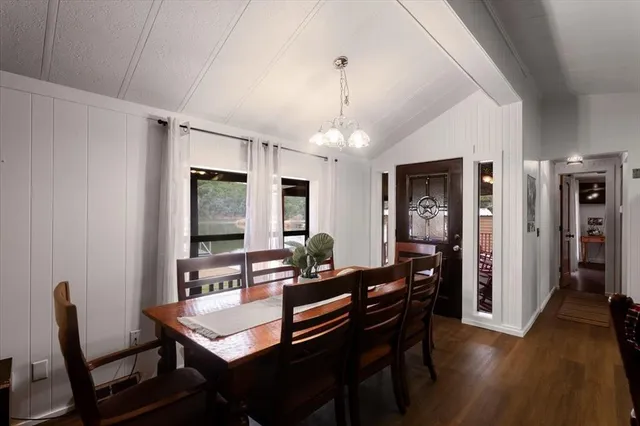 a dining room with wooden floor a chandelier a wooden table and chairs