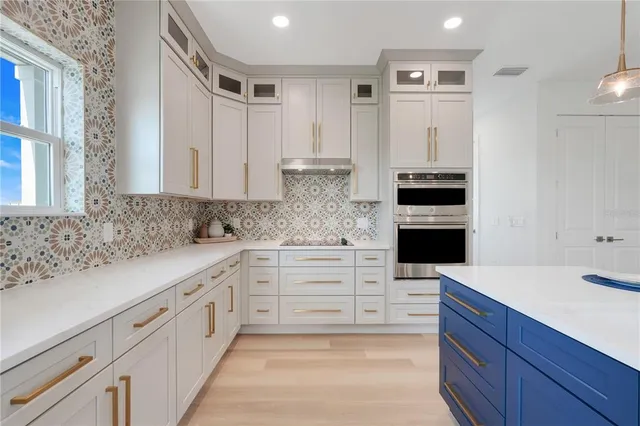 a kitchen with granite countertop white cabinets and stainless steel appliances