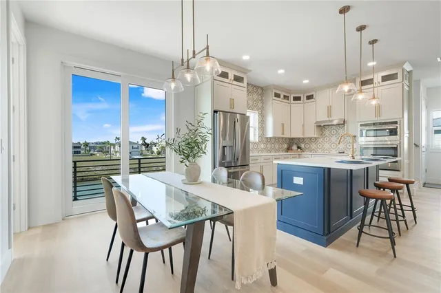 a kitchen with stainless steel appliances kitchen island granite countertop a dining table chairs and granite counter tops