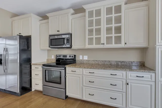 a kitchen with granite countertop white cabinets and stainless steel appliances
