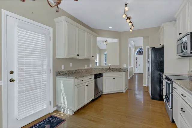a kitchen with granite countertop a sink cabinets stainless steel appliances and a window