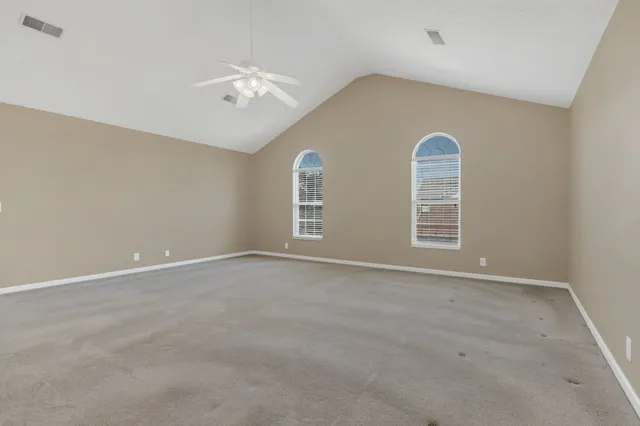 an empty room with windows and ceiling fan