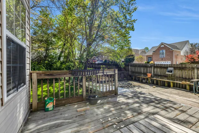 a view of house with deck outdoor seating and trees in the background