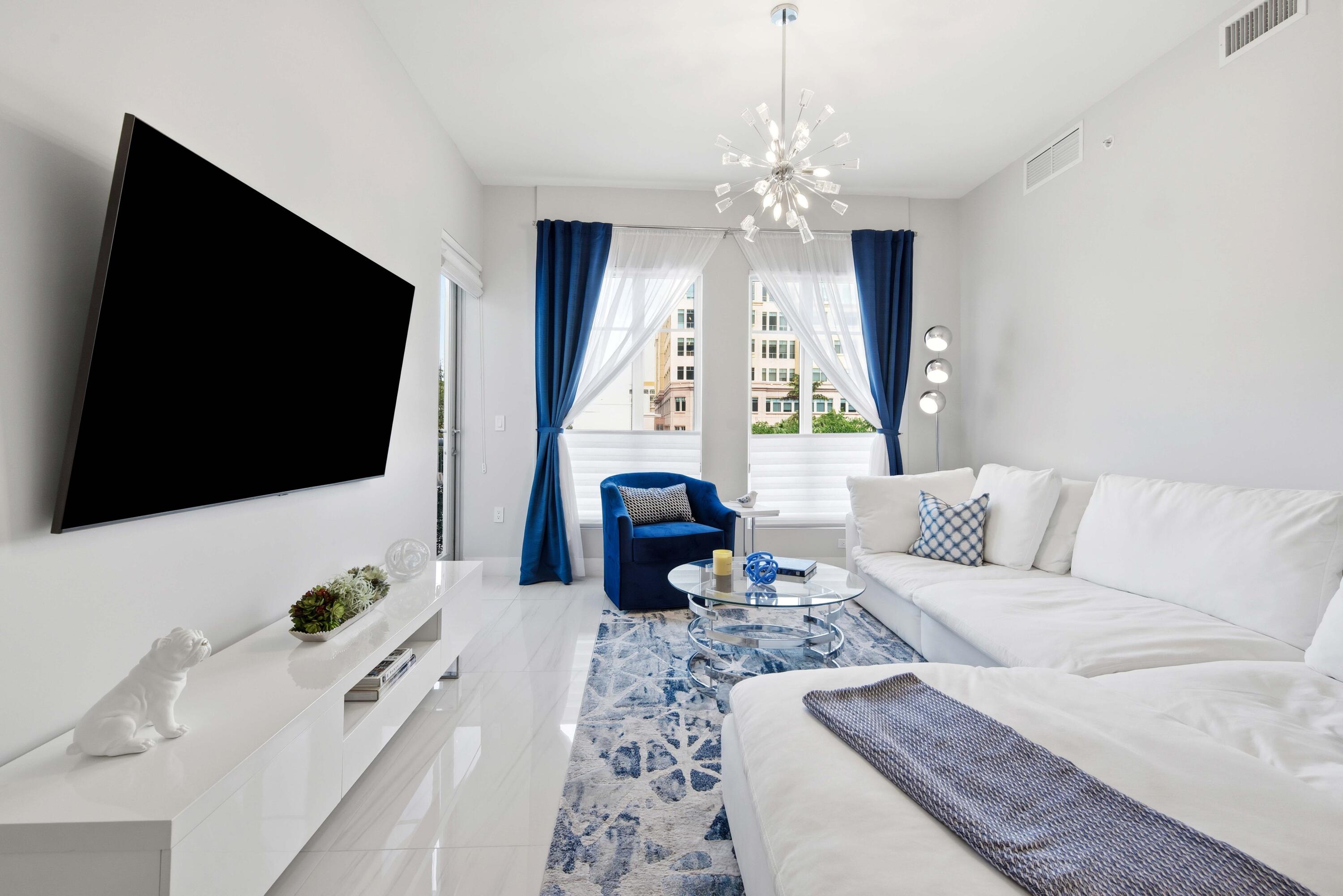 155 East Boca Raton Road, Unit 313 Boca Raton, FL 33432 - Photo 18 of 72 a living room with furniture a flat screen tv and a chandelier