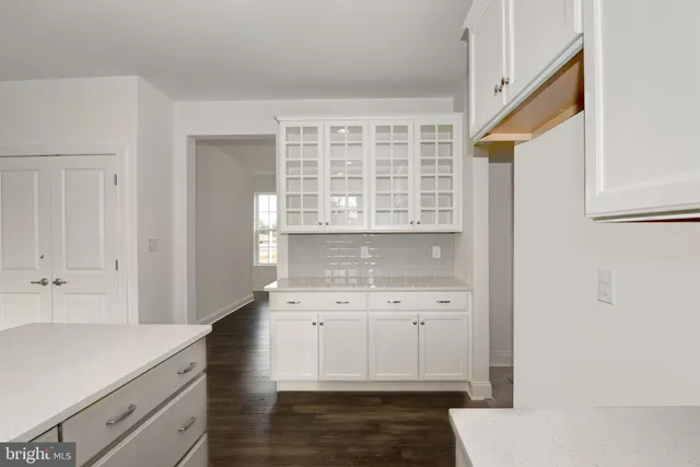 a kitchen with a sink dishwasher a stove and white cabinets with wooden floor