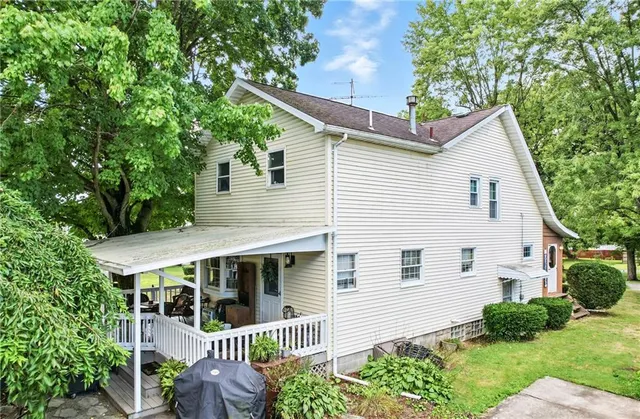 a view of a white house with a small yard and large tree