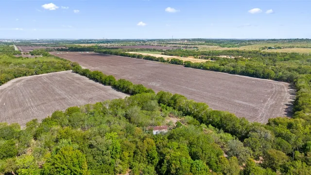 an aerial view of a houses with outdoor space and trees all around