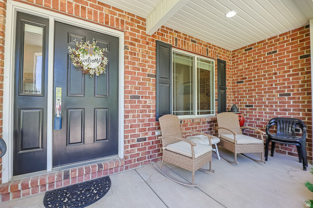 31 Village Square Road Centerville, UT 84014 - Photo 3 of 29 Brick exterior with a covered porch, featuring a paneled entry door with sidelight, and a window with dark shutters