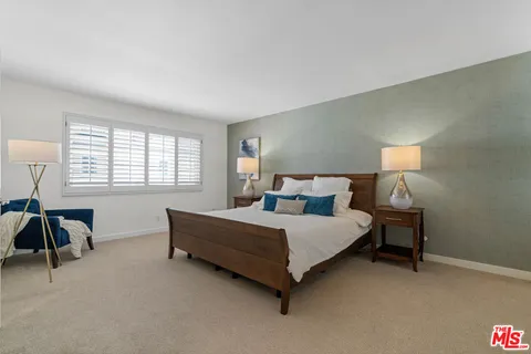 a spacious bedroom with a bed and a lamp next to a window