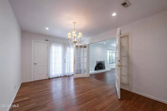 a view of a room with wooden floor chandelier and windows