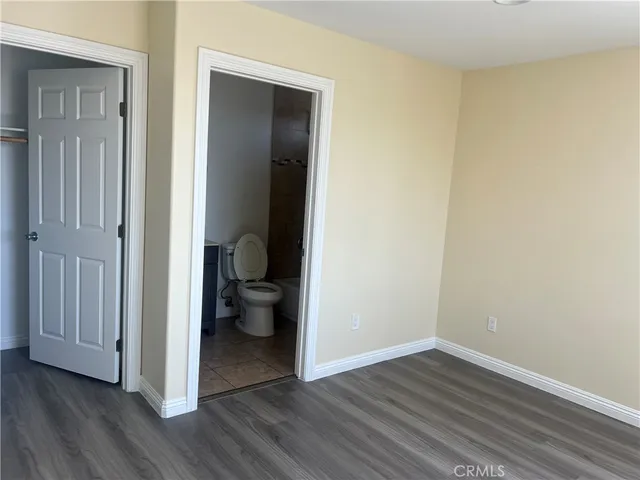 a view of a hallway with wooden floor and a bathroom