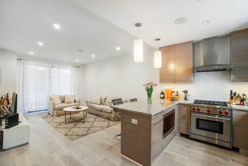 a living room with stainless steel appliances kitchen island granite countertop a stove and a sink