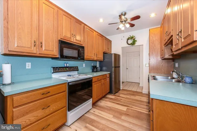 a kitchen with stainless steel appliances granite countertop a sink a stove cabinets and wooden floor