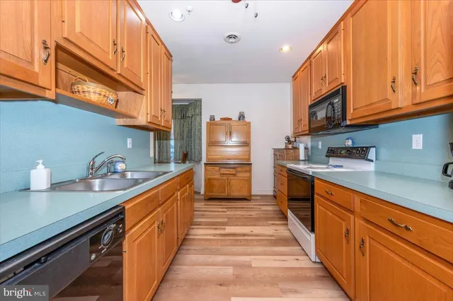 a kitchen with granite countertop a sink and dishwasher a stove top oven with wooden floor