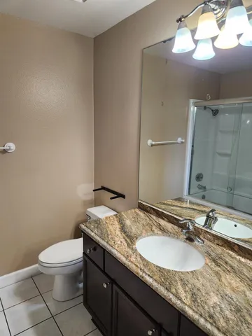 a bathroom with a granite countertop sink a toilet and a mirror