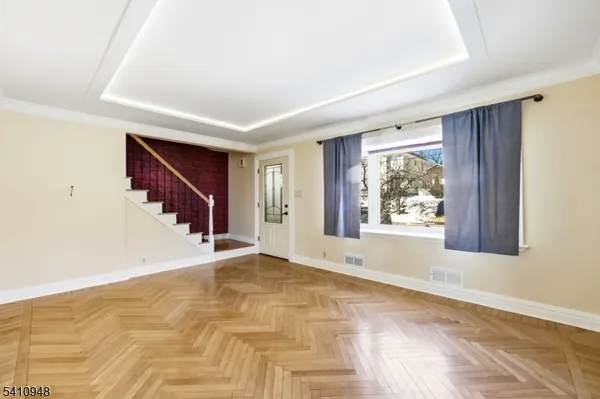 a view of an empty room with wooden floor and stairs