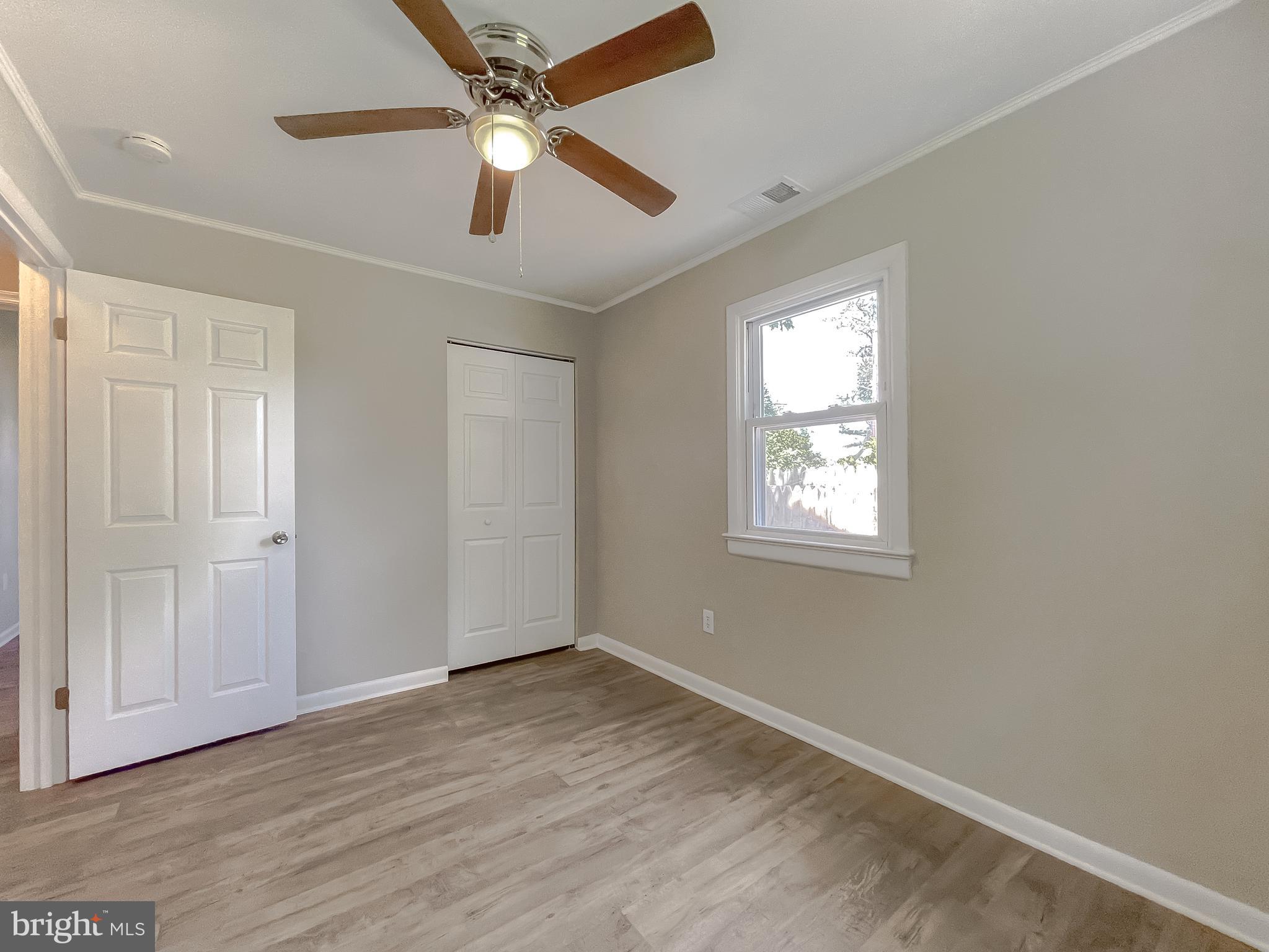 1607 Beech Road St. Leonard, MD 20685 - Photo 31 of 33 an empty room with wooden floor ceiling fan and windows