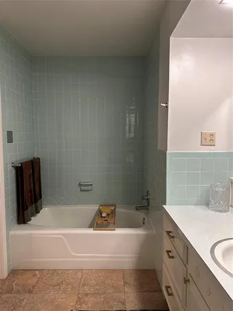 a bathroom with a tub a sink and granite