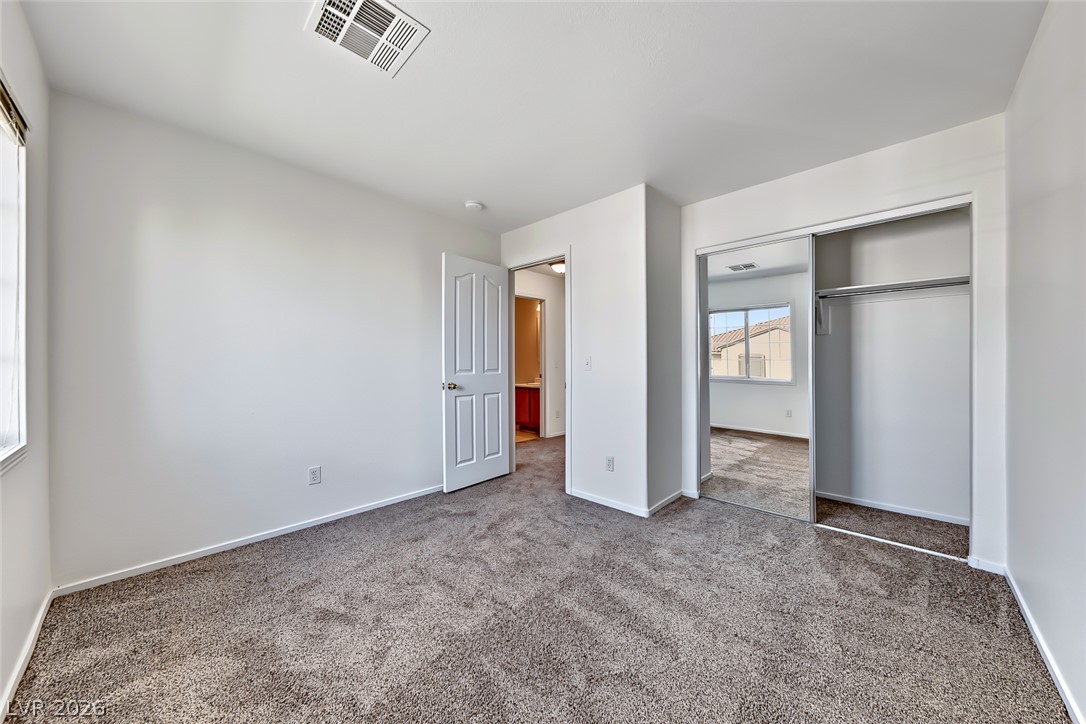 205 Genesee Point Street Henderson, NV 89074 - Photo 20 of 30 Soft carpeted flooring and sliding mirrored closet doors define this comfortable secondary bedroom.