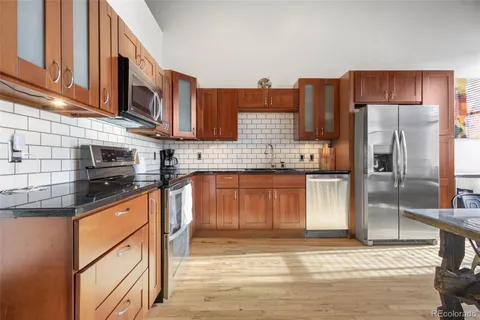 a kitchen with stainless steel appliances granite countertop a refrigerator a stove and a sink