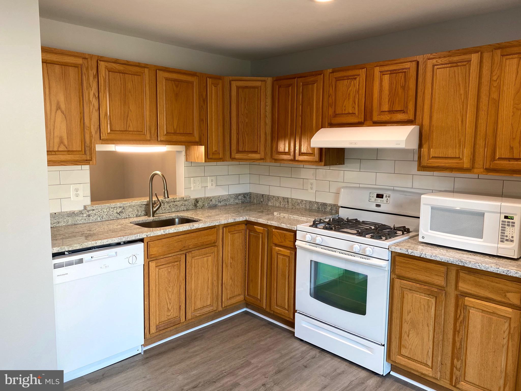 8081 Barcarole Court Springfield, VA 22153 - Photo 18 of 64 a kitchen with granite countertop wooden cabinets and white appliances