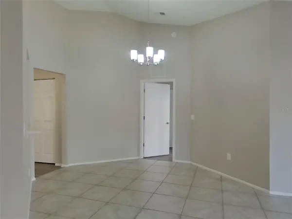 a view of an empty room with a chandelier fan