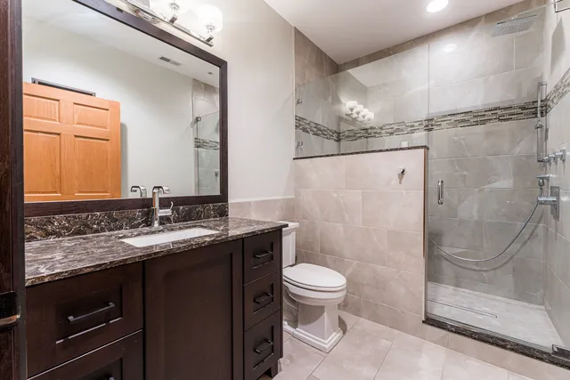 a bathroom with a granite countertop sink toilet and shower