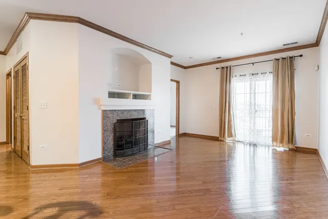 a view of an empty room with wooden floor fireplace and a window
