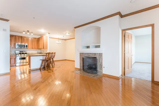 a living room with stainless steel appliances furniture a fireplace and a kitchen view