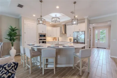 a kitchen with kitchen island granite countertop a stove a sink a dining table and chairs with wooden floor