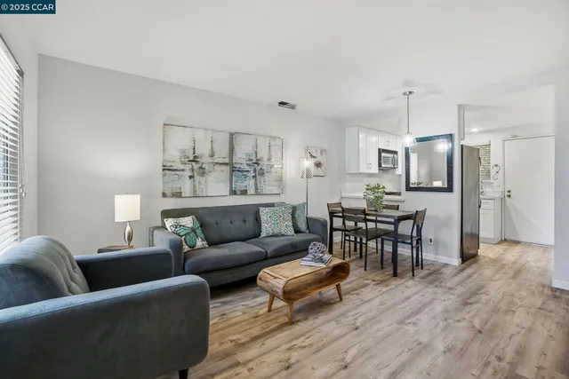 a living room with furniture wooden floor and kitchen view