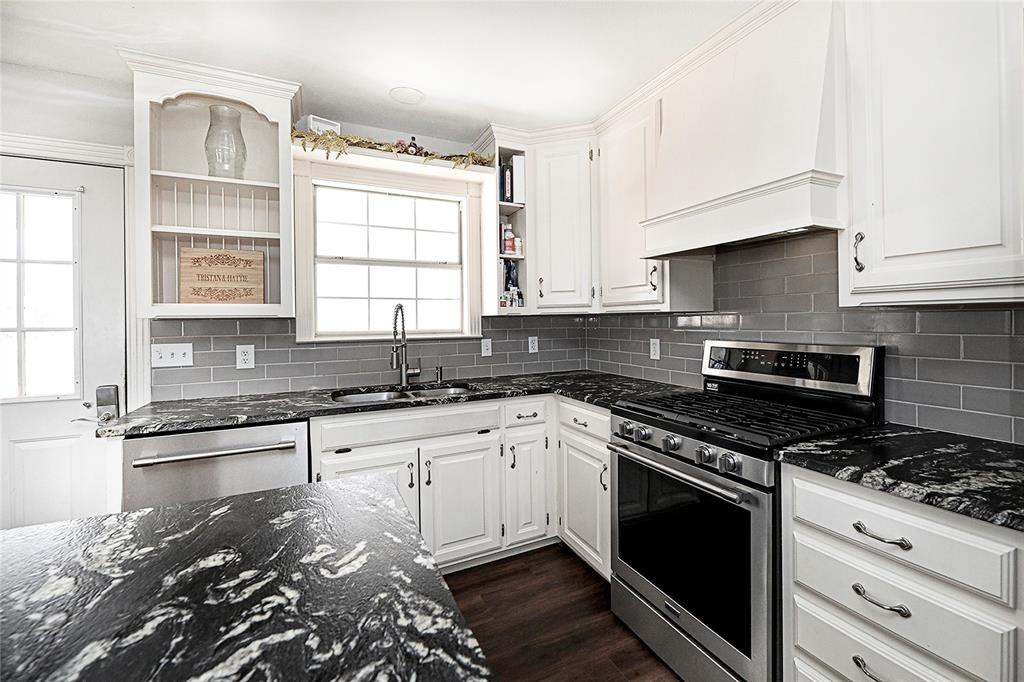 1364 Winn Road Bowie, TX 76230 - Photo 14 of 38 a kitchen with granite countertop a stove sink and cabinets