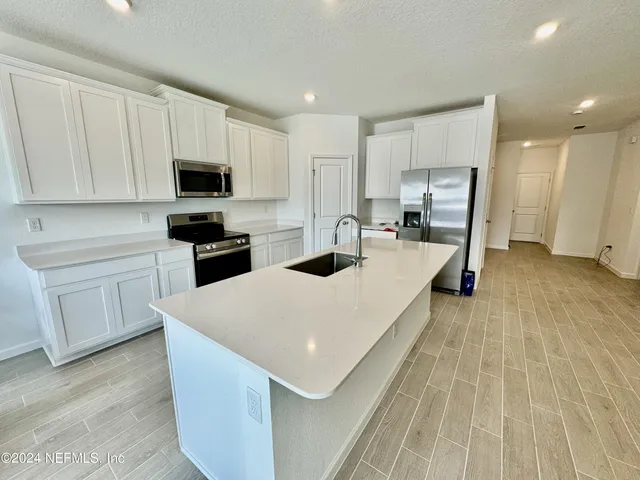 a large white kitchen with a stove a sink a microwave and cabinets