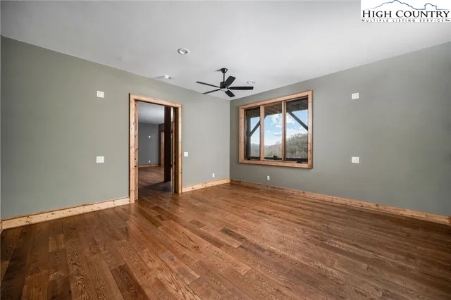 a view of an empty room with a window and wooden floor